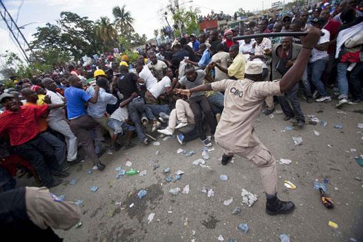 پولیس در حال لت و کوب کردن  هواداران رییس جمهور سابق هائیتی در بیرون محکمه در 8 می
