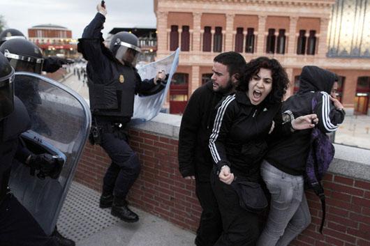 پولیس ضد شورش در حال زدن باتوم به معترضین اسپانیایی در نزدیکی پارلمان اسپانیا در 25 آپریل