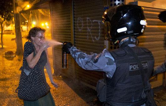یک افسر پولیس در حال پاشیدن اسپری فلفل به یک زن معترض در 17 ژوئن در ریو برازیل