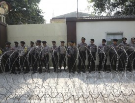 Police officers stand guard behind a razor wire barricade during a rally against persecution of Myanmar